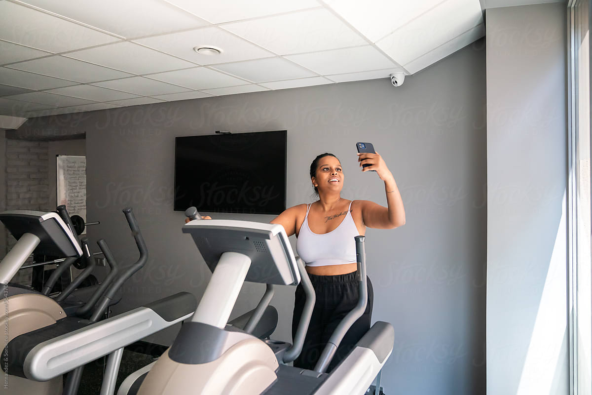 Curvy Woman Using Cellphone Working Out In The Gym
