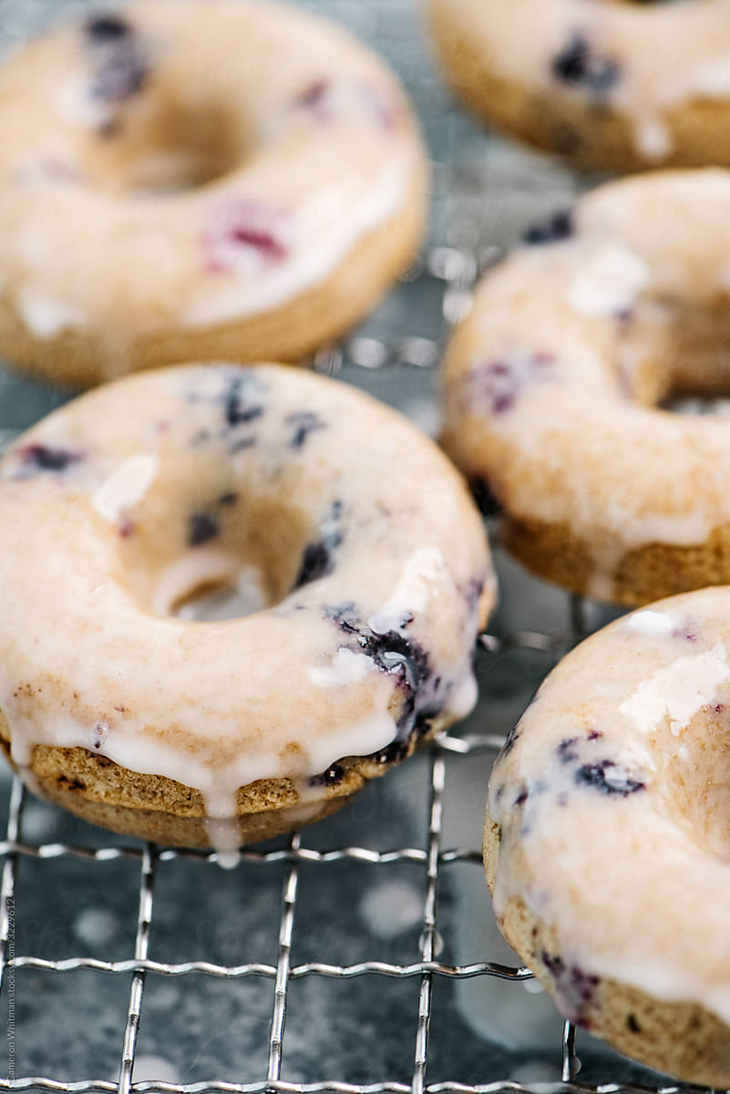 Baked and glazed blueberry donuts drying on a rack