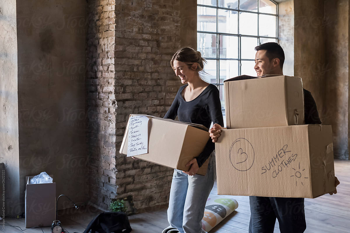 Couple holding moving boxes in new home