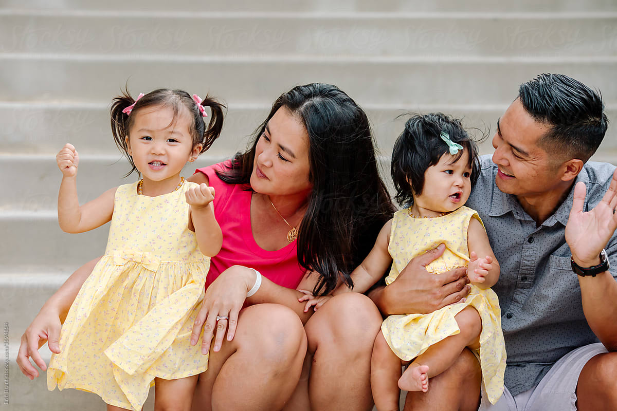 Asian parents with sweet young daughters on steps