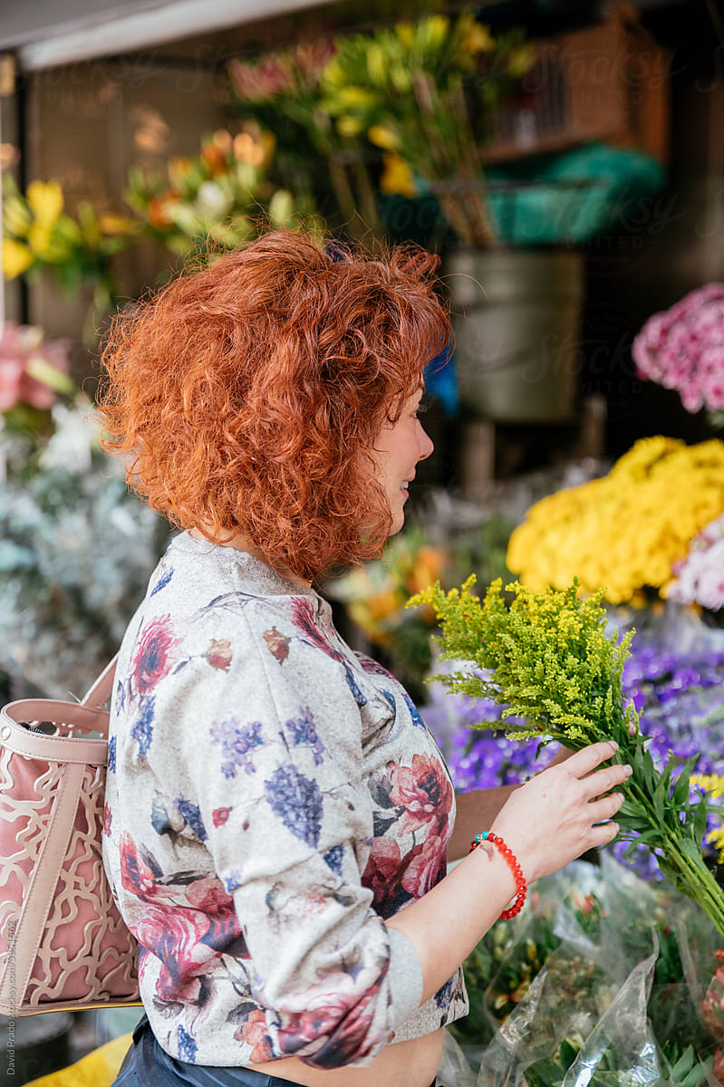 Charming woman choosing flowers in floral shop