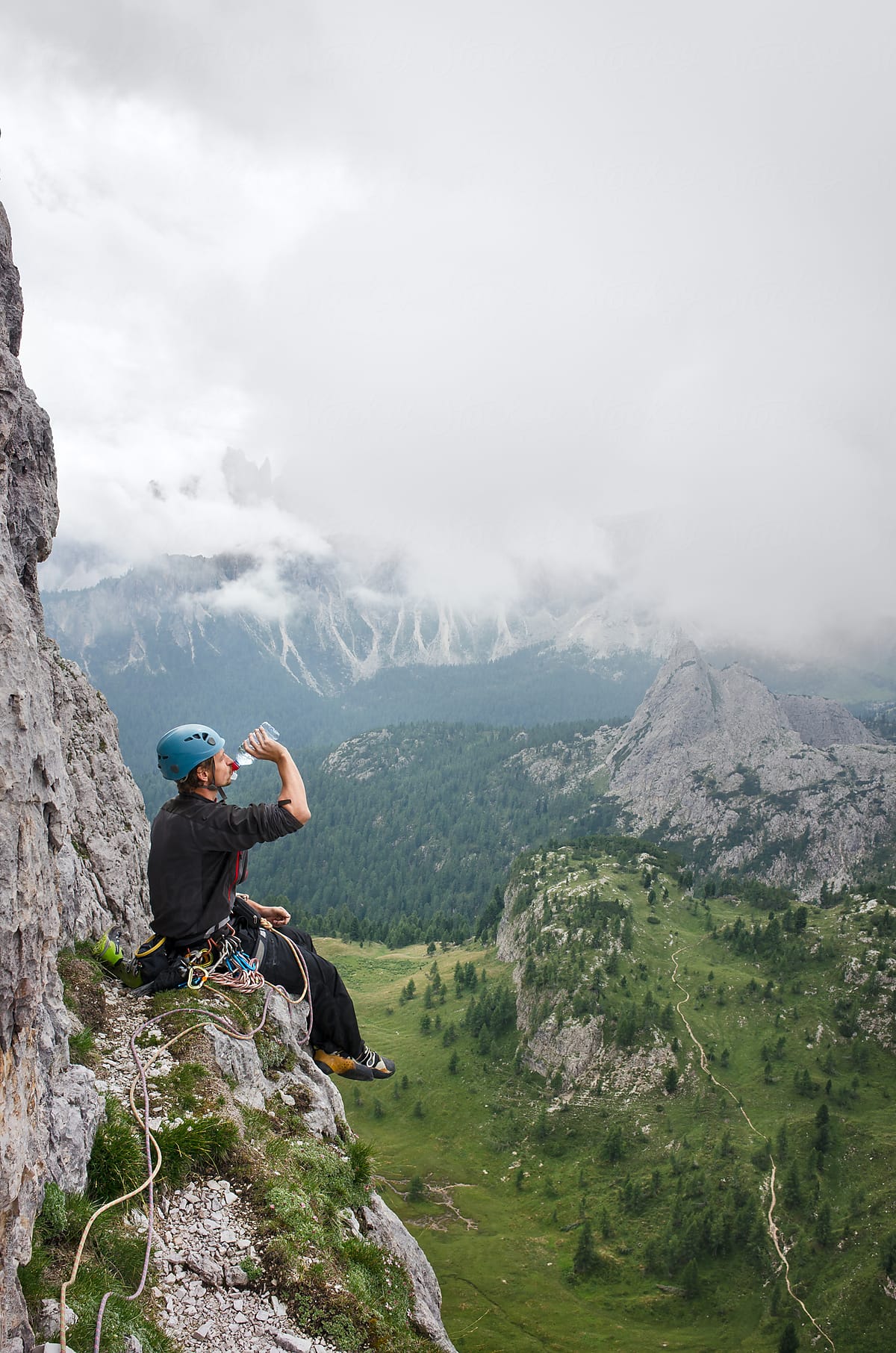 Alpinist resting on a rock ledge high above the ground