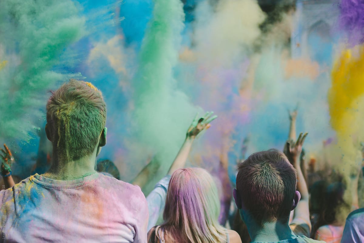 partypeople throwing colorful powder in the air at a music festival