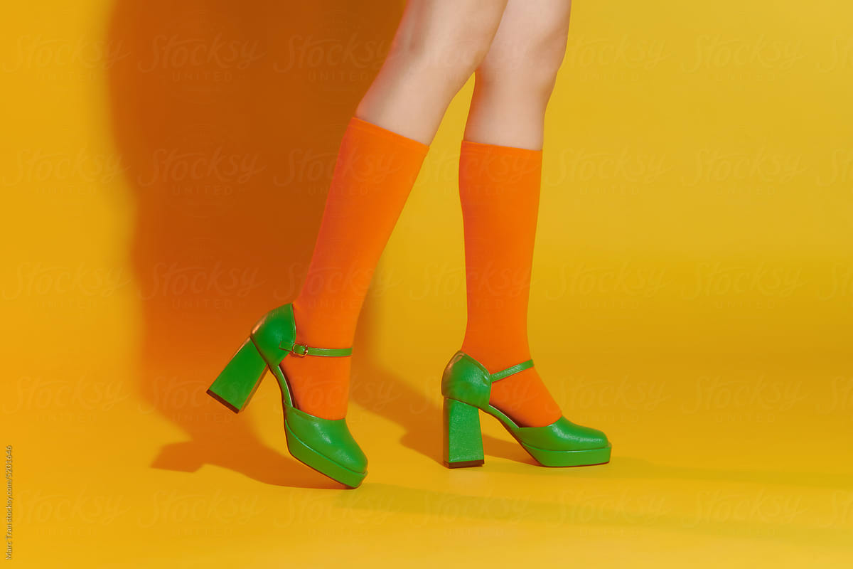 Woman wearing bright socks and shoes on color background