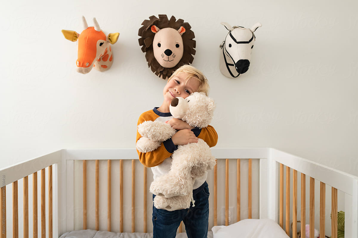 Boy hugs stuffed bear in his room