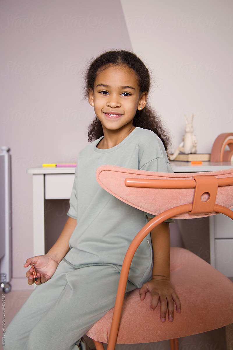Smiling black kid with Afro hair sitting on chair