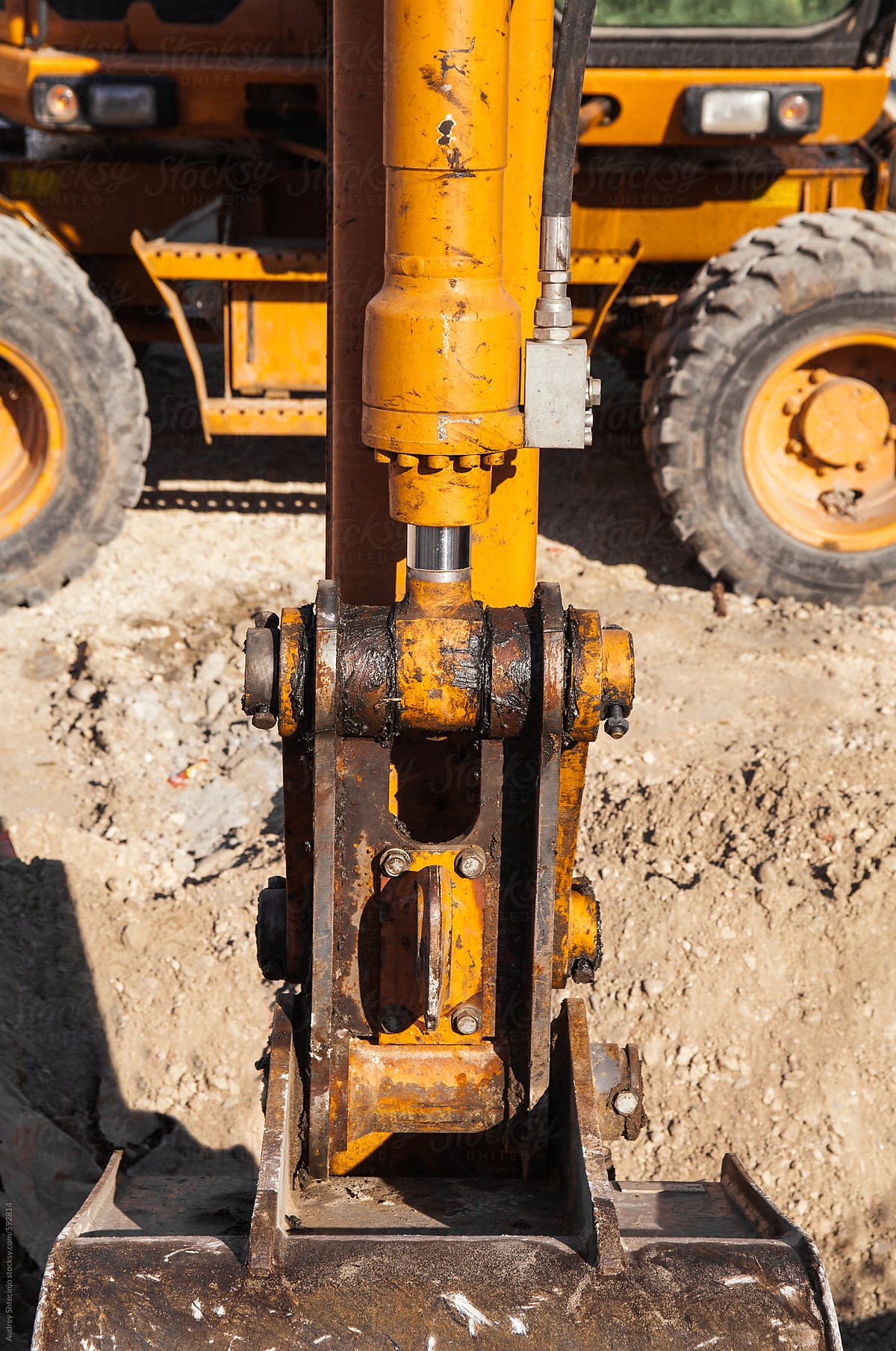 Excavator hydraulic arm excavating earth/close up