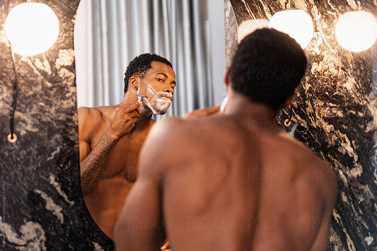 Shirtless Black Man Shaving In Front Of The Mirror