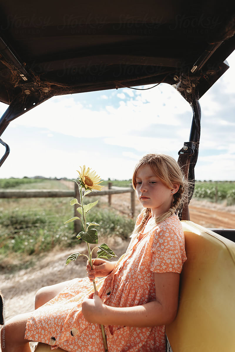 girl sitting in ATV beside sunflower crop