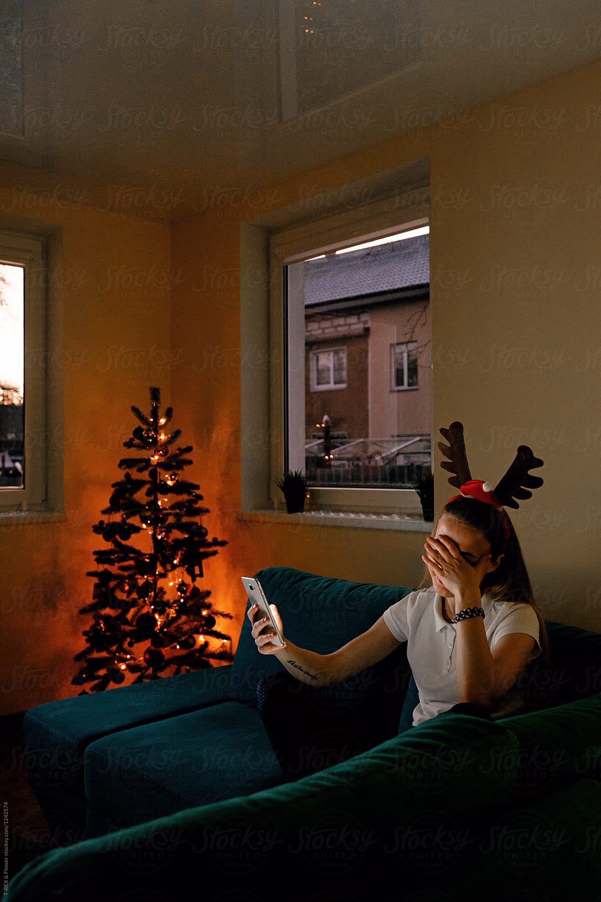 Girl in antlers taking selfie at home