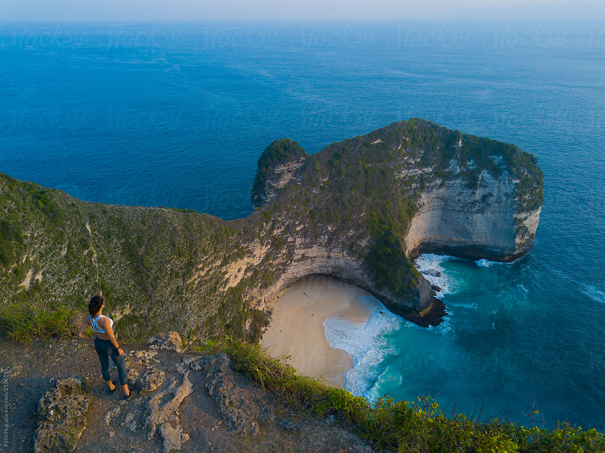An asian woman is enjoying the spectacular view over Nusa Penidas Kelingking Beach