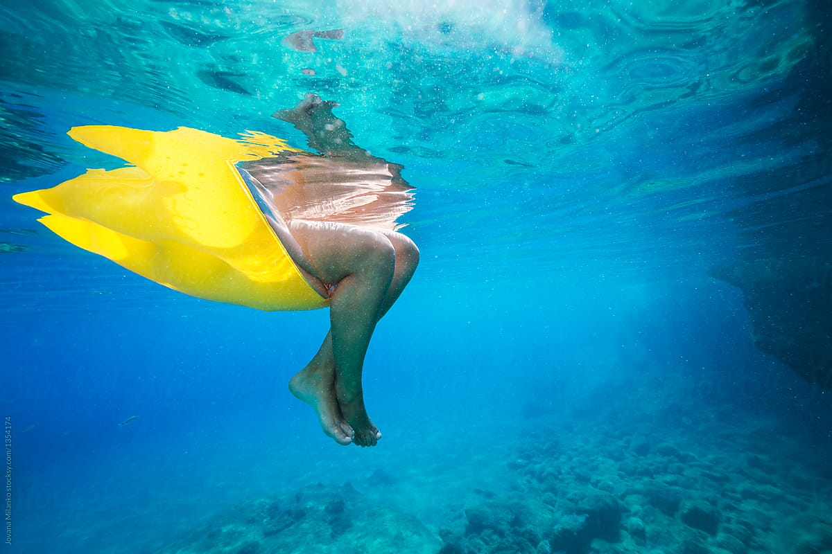 Woman sitting on an inflatable mattress cooling her feet in the sea