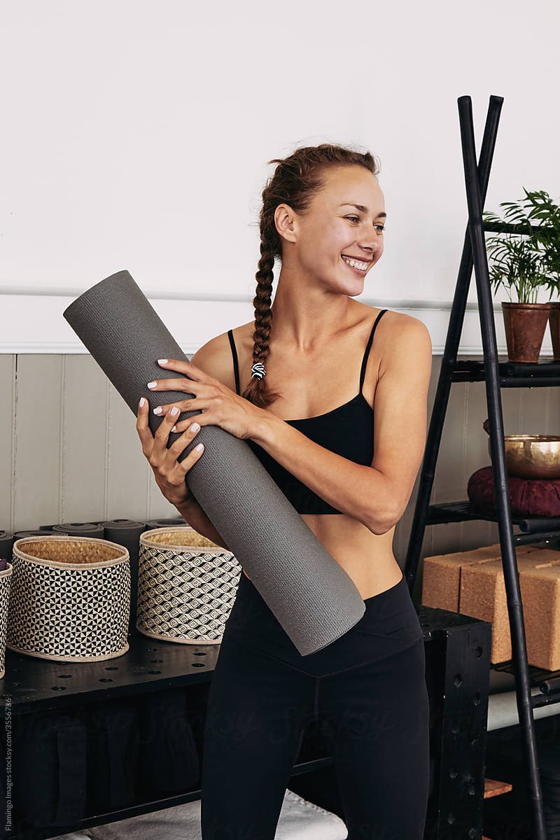 Smiling woman holding a yoga mat