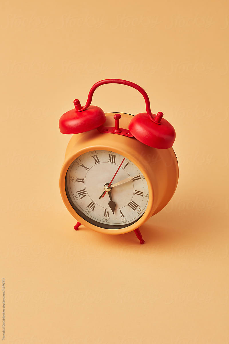Old yellow alarm clock with red bells on an yellow background, copy space.