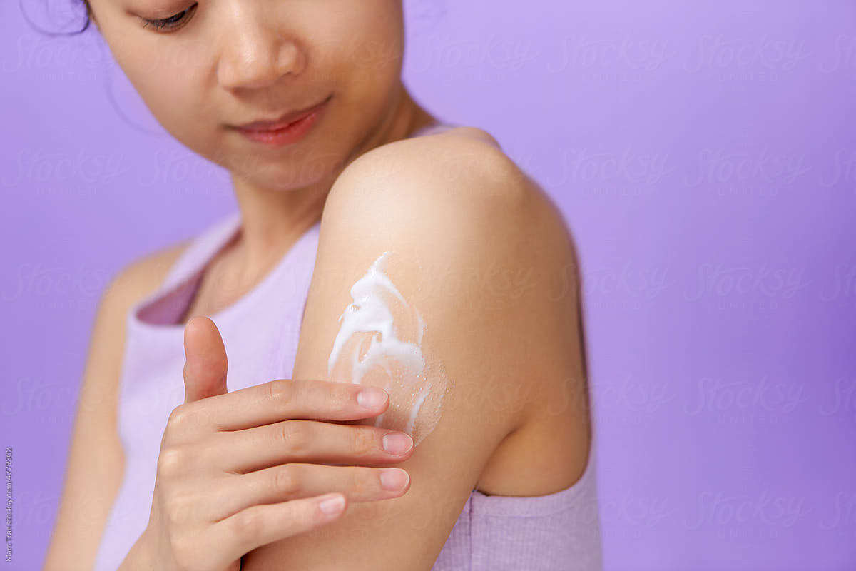 woman cares about her shoulder applying cosmetic cream