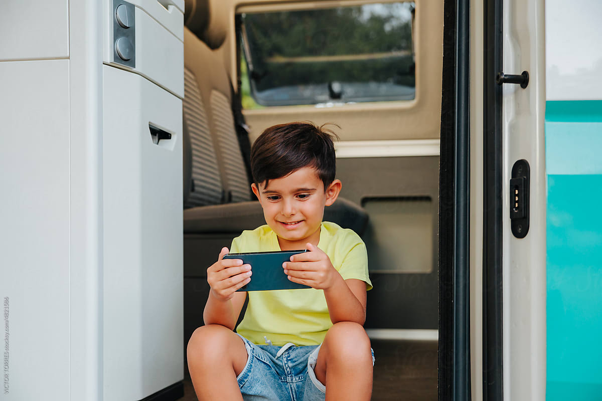 Cheerful boy using tablet in camper