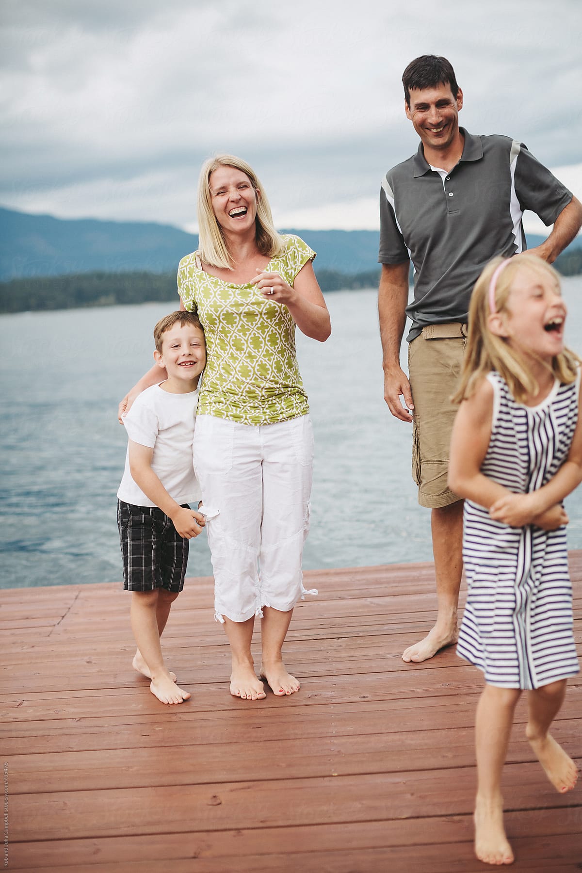 Family of four laughing on the dock at the lake
