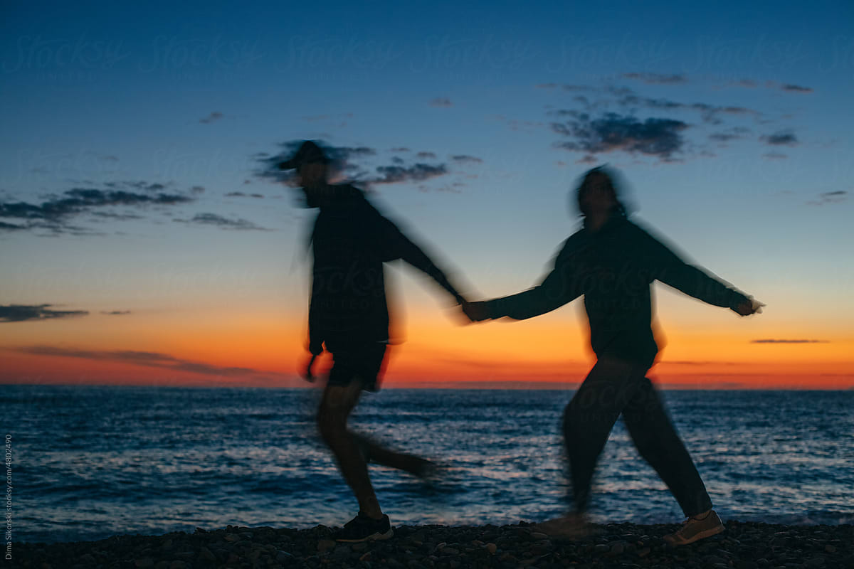 A couple in love in motion walks on a beautiful sunset on the beach