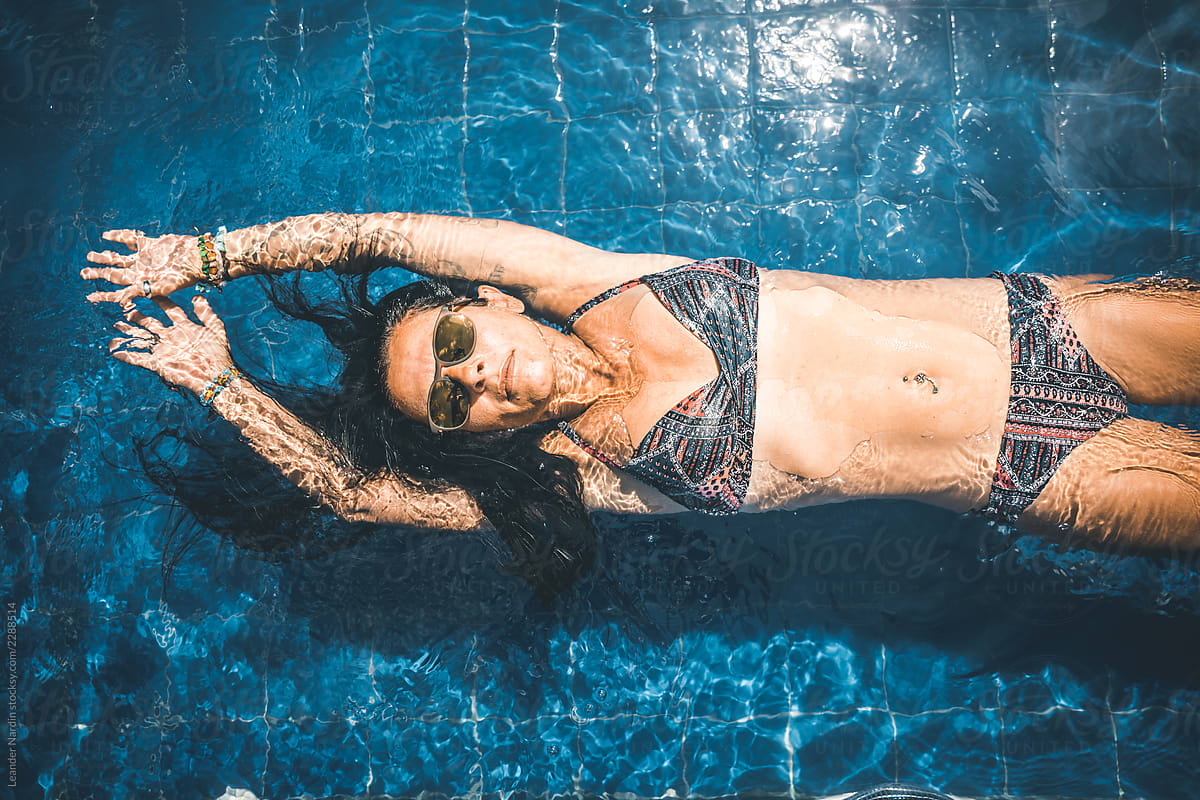 Beauty In Bikini And Denim Shirt Listening Music At A Pool by Stocksy  Contributor Akela - From Alp To Alp - Stocksy