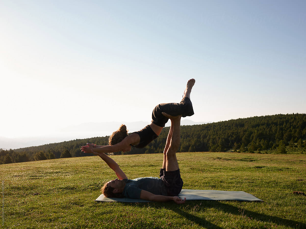 Flexible couple practicing acro yoga on lawn
