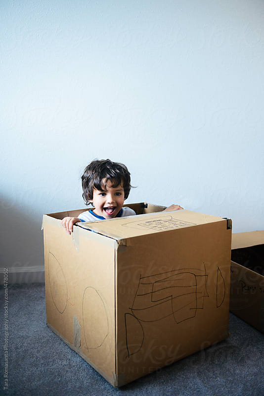 preschool boy plays in a cardboard box decorated as a car