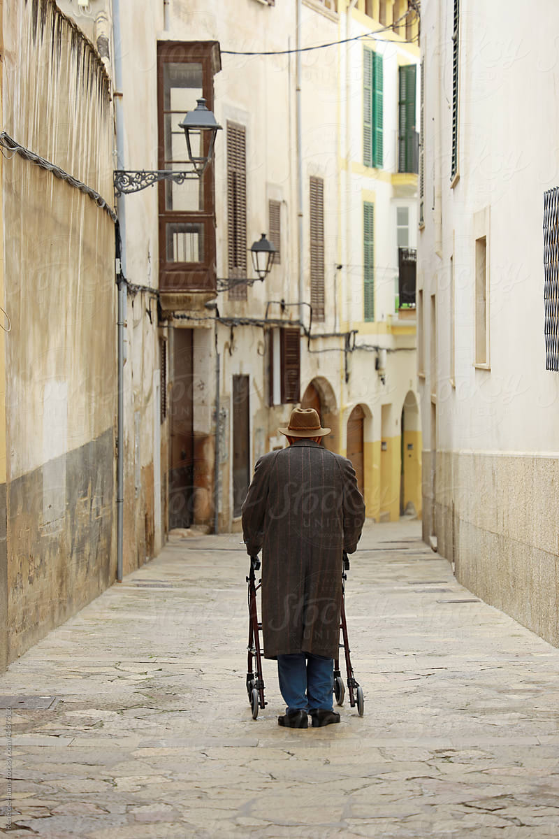 old man with walker in small street