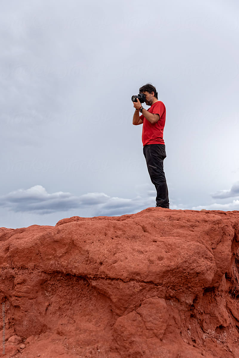 Photographer taking pictures of red earth formations