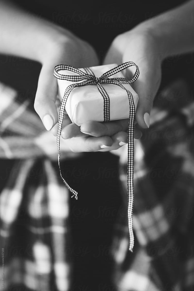 Black and white of female hands holding a small gift - vertical