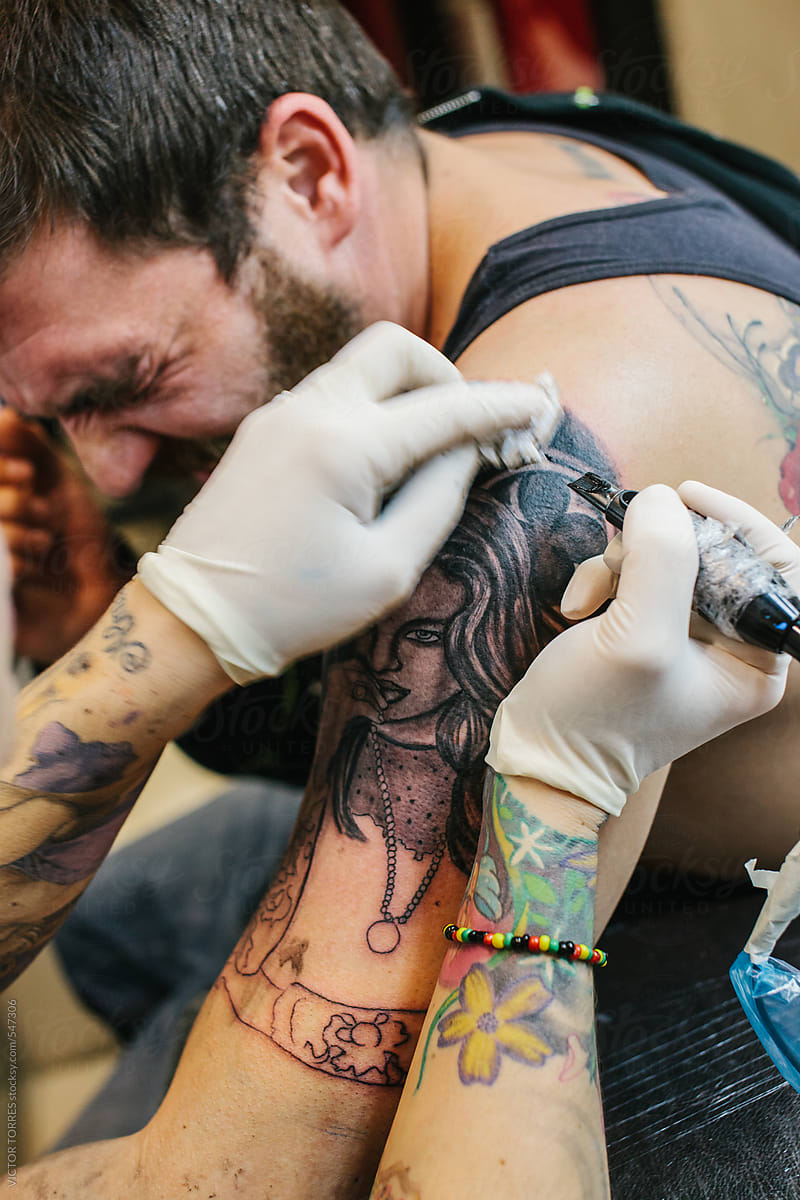 Tattoo Artist Working on a Man\'s Arm
