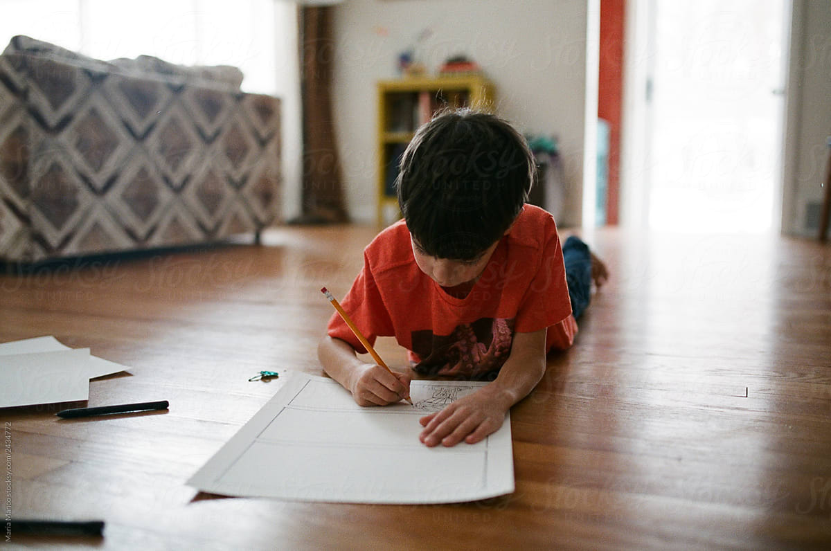 boy draws on the floor of his home