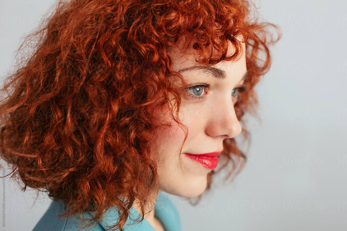Serene curly red hair woman in studio