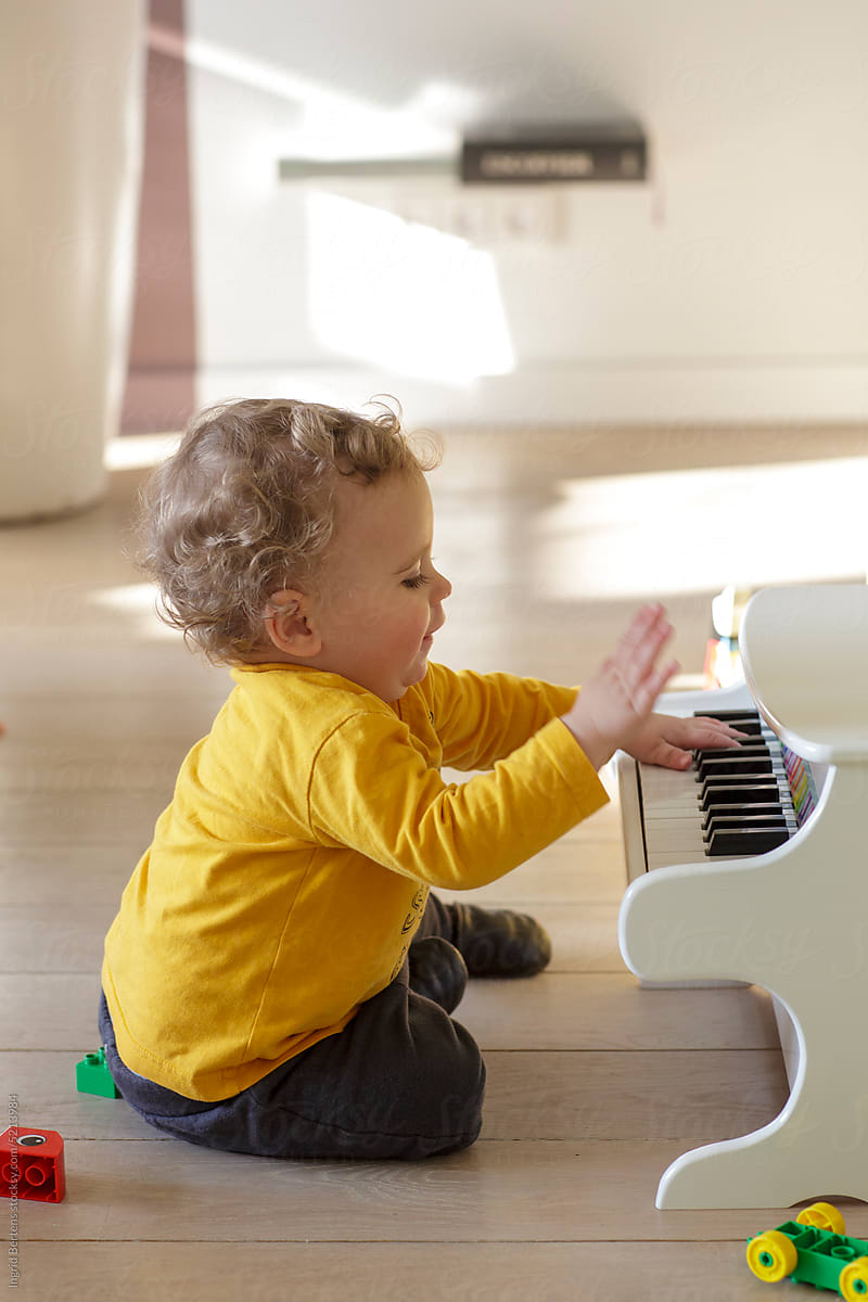 Toddler plays the toy piano.