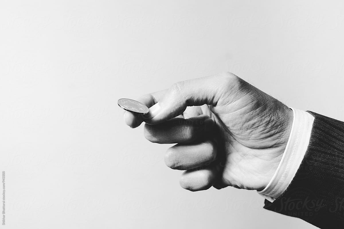 Hand of a businessman about to toss a coin.