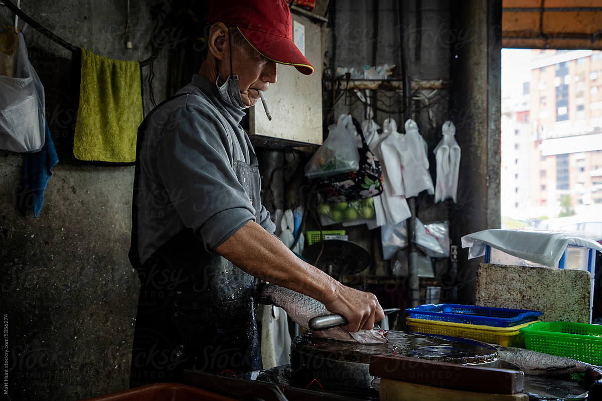 A vendor smokes a cigarette while chopping fish in Taiwan