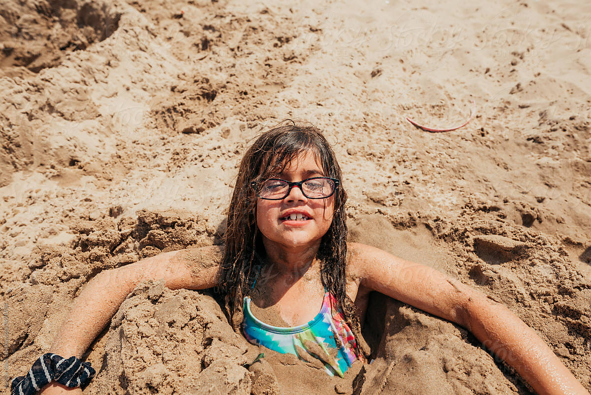 Girl buried in the sand.