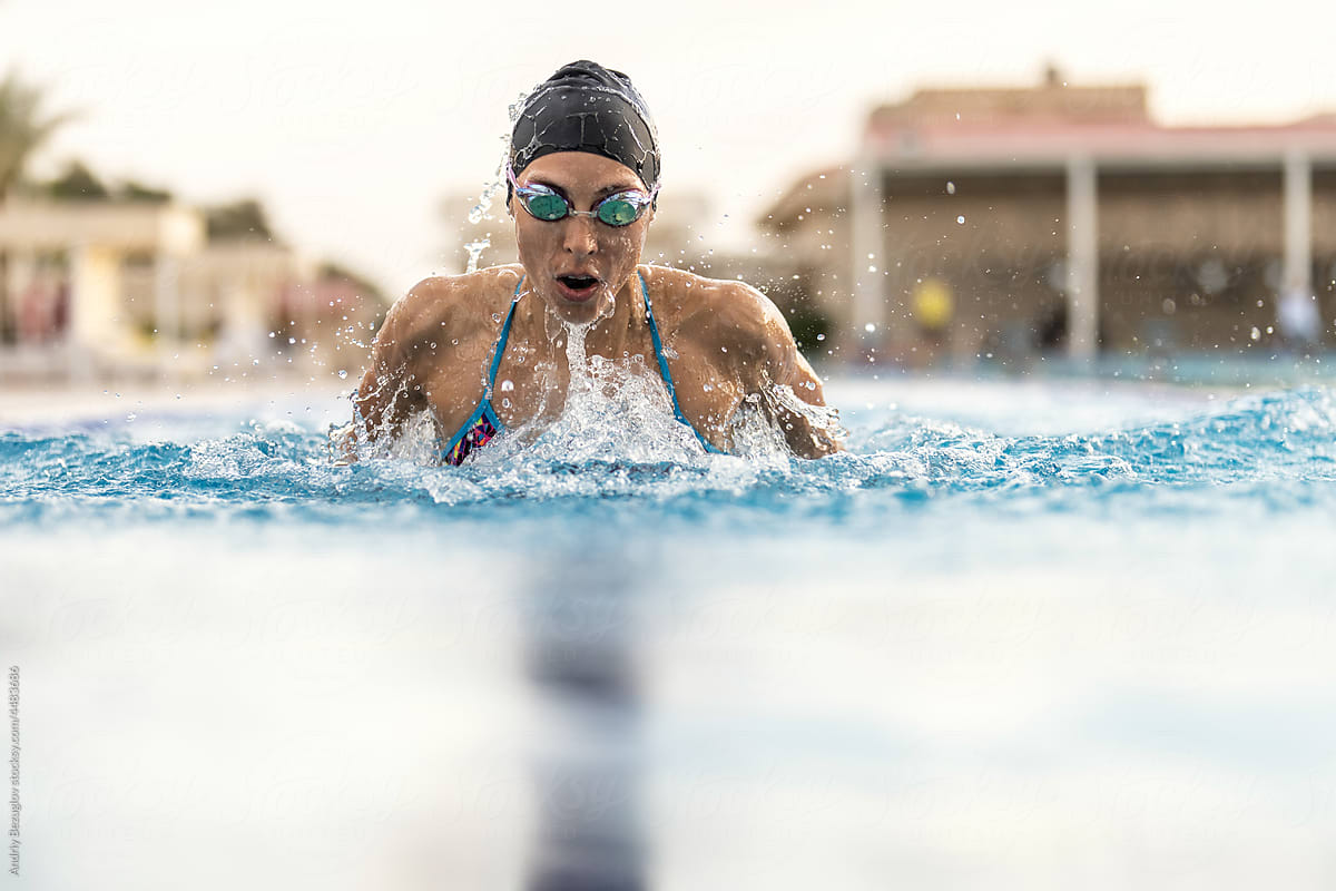 Girl is swimming in outdoor pool during her training