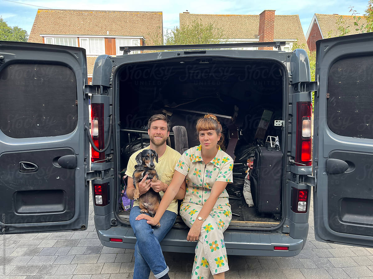 A couple and their dog with a moving van