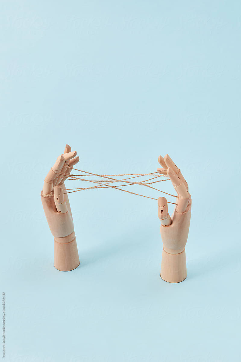 Wooden doll\'s hands are playing a Cat\'s cradle game.