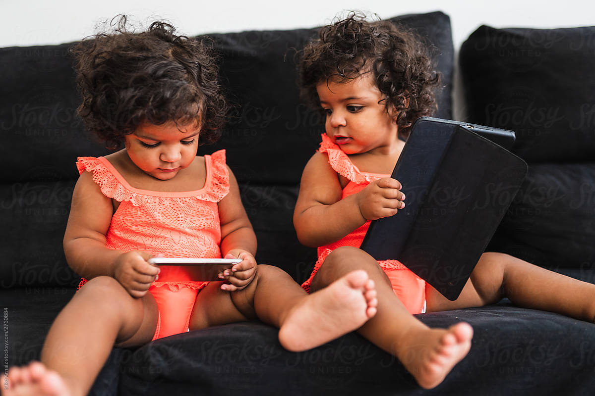 identical twin girls sitting together on the sofa.