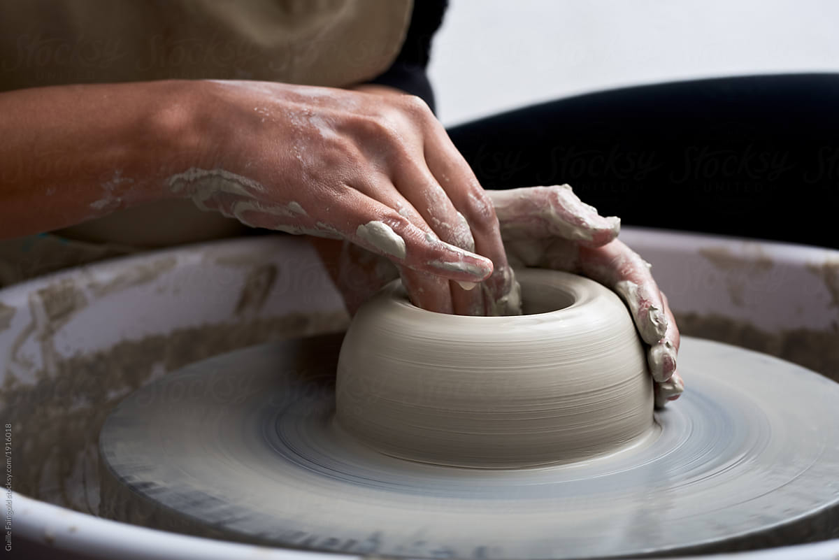 Hands making pottery in workshop.