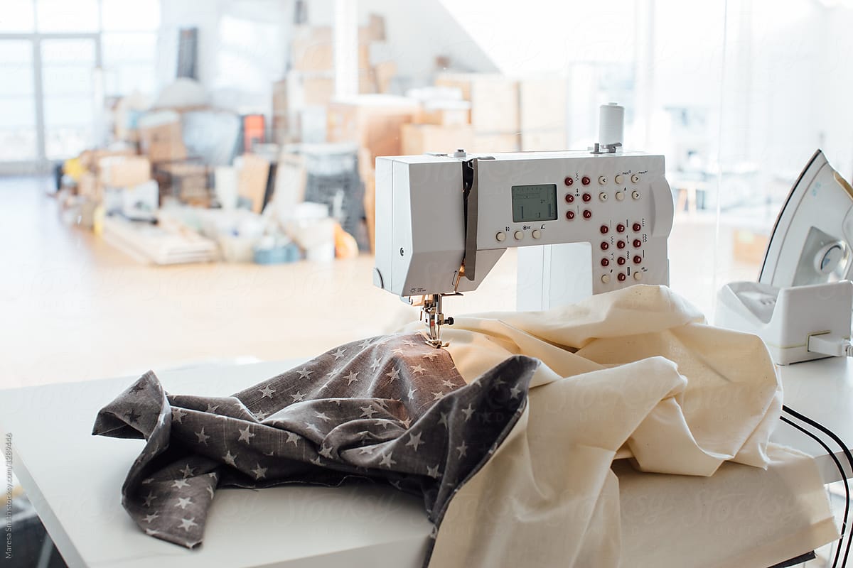 A sewing machine on a tidy desk stitching star-patterned and calico fabric