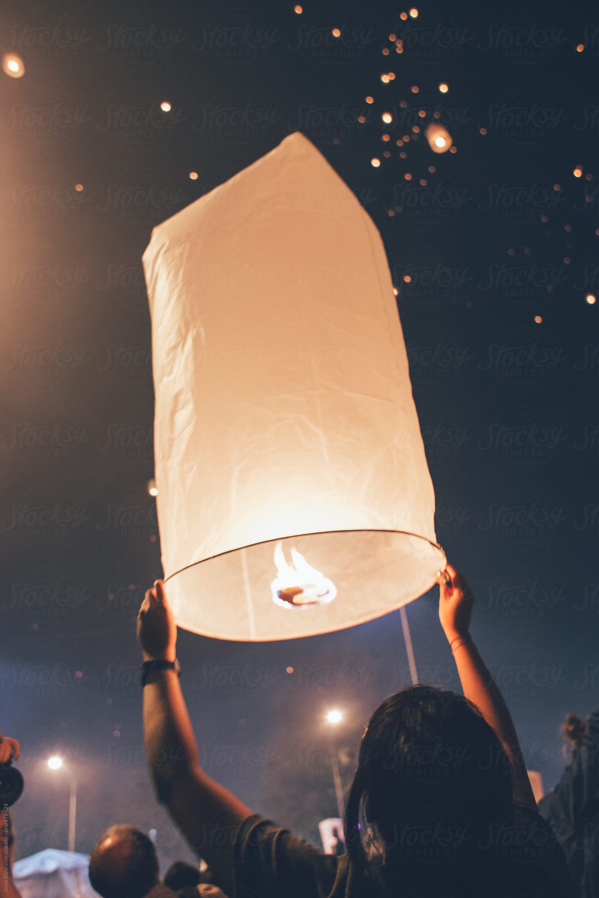Festival time - woman releasing paper lantern in sky