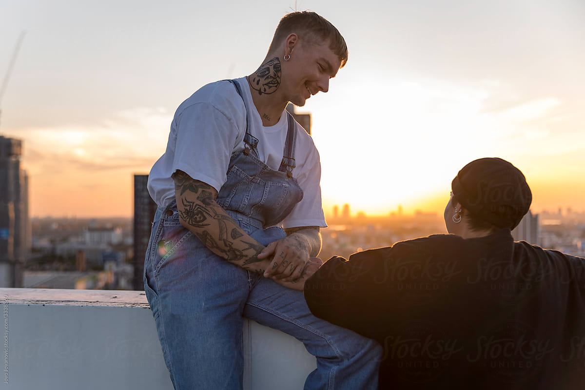 tattooed  man smiling at girlfriend at sunset