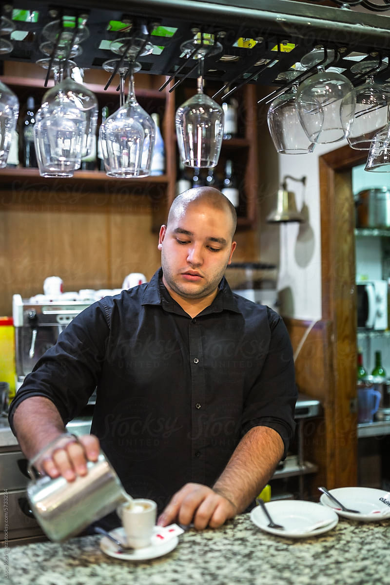 young waiter serving coffee in a bar