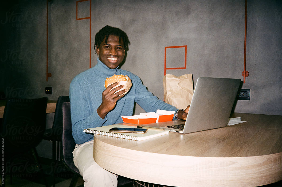 Black manager eating burger during work