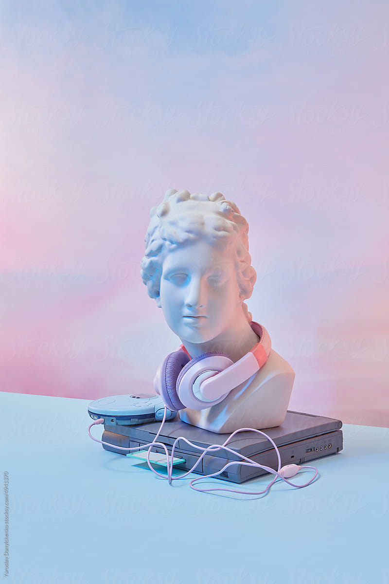 Statue with headphones, CD player and old laptop.