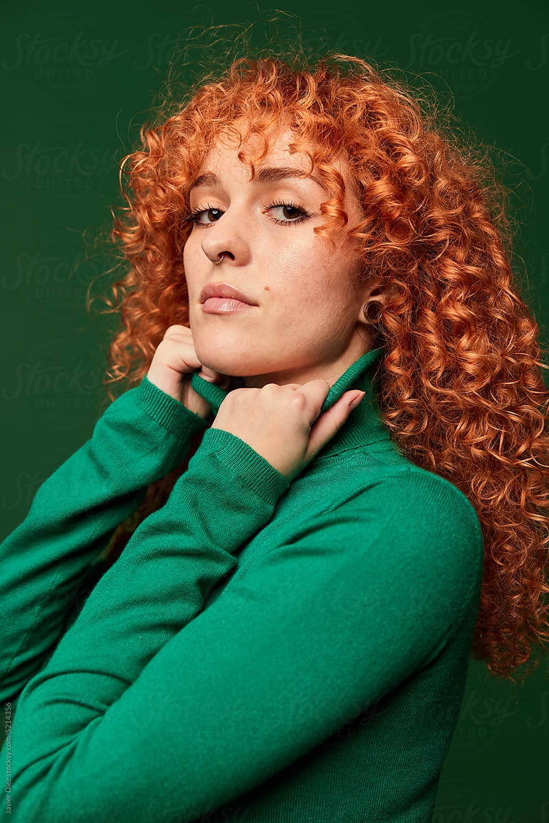 Attractive young ginger woman on green background