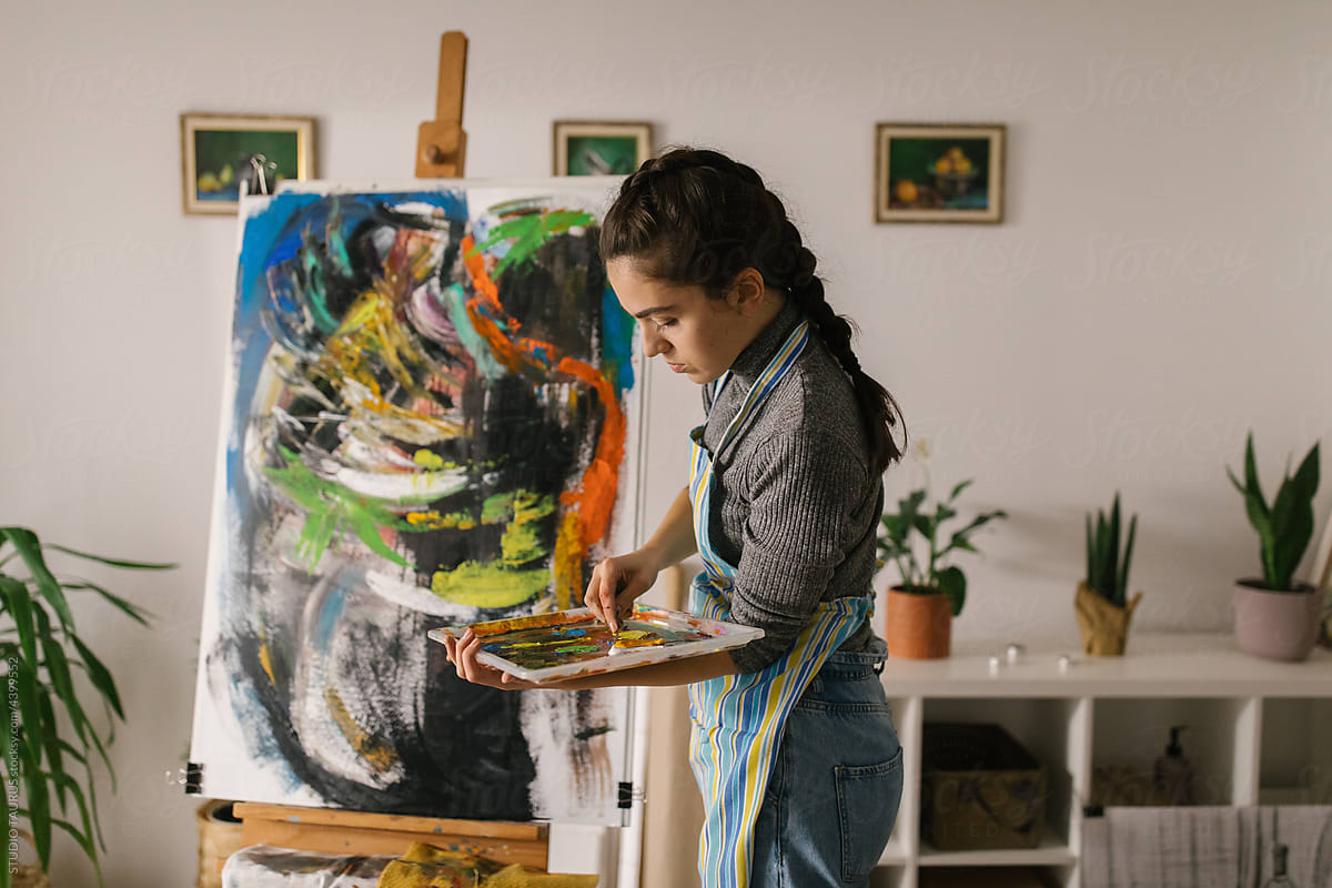 Female artist painting on canvas in home studio