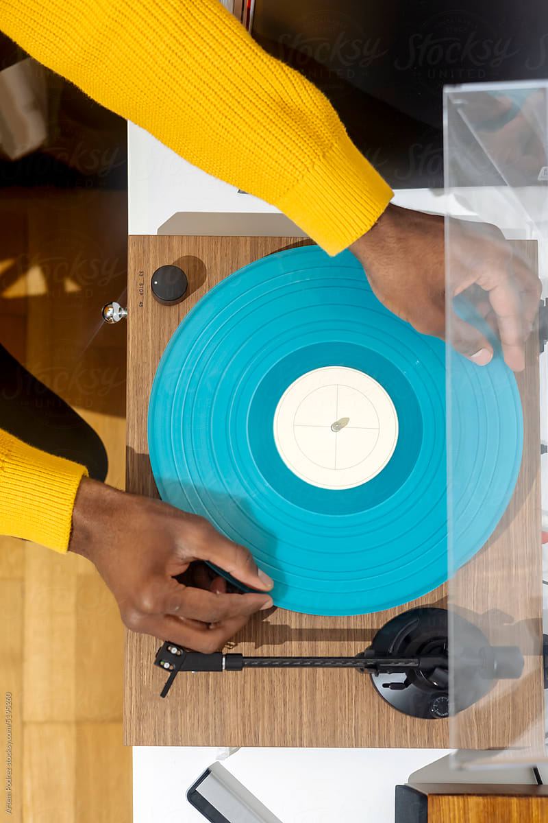 Close-up of black hands installing a vinyl record in a turntable