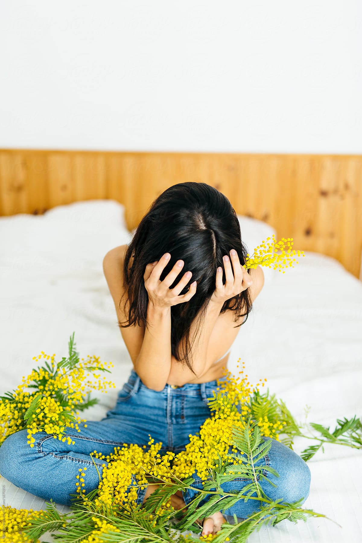 brunette girl with mimosa plants covering her face